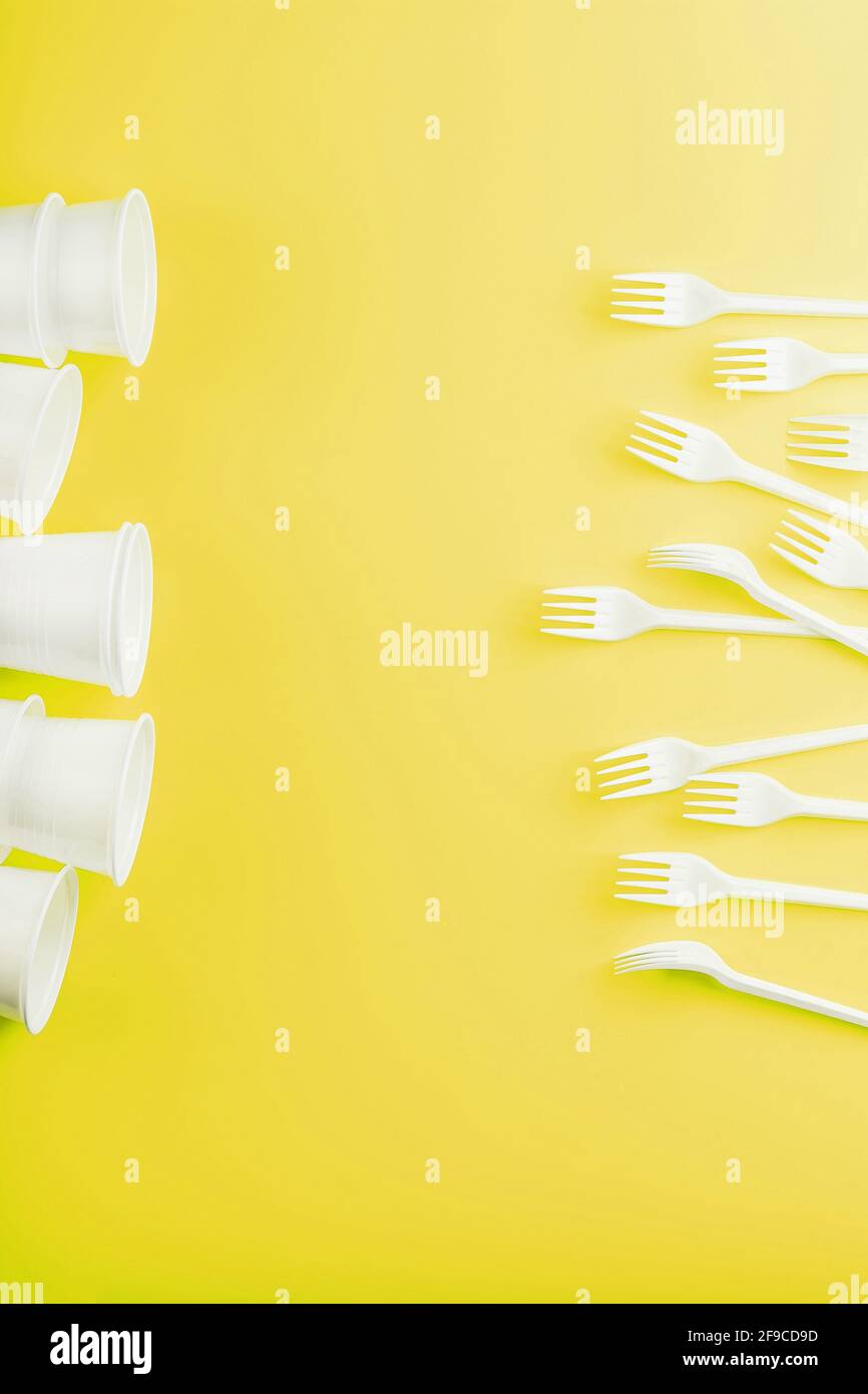 Plastic tableware on a yellow background with free space. Disposable tableware Stock Photo