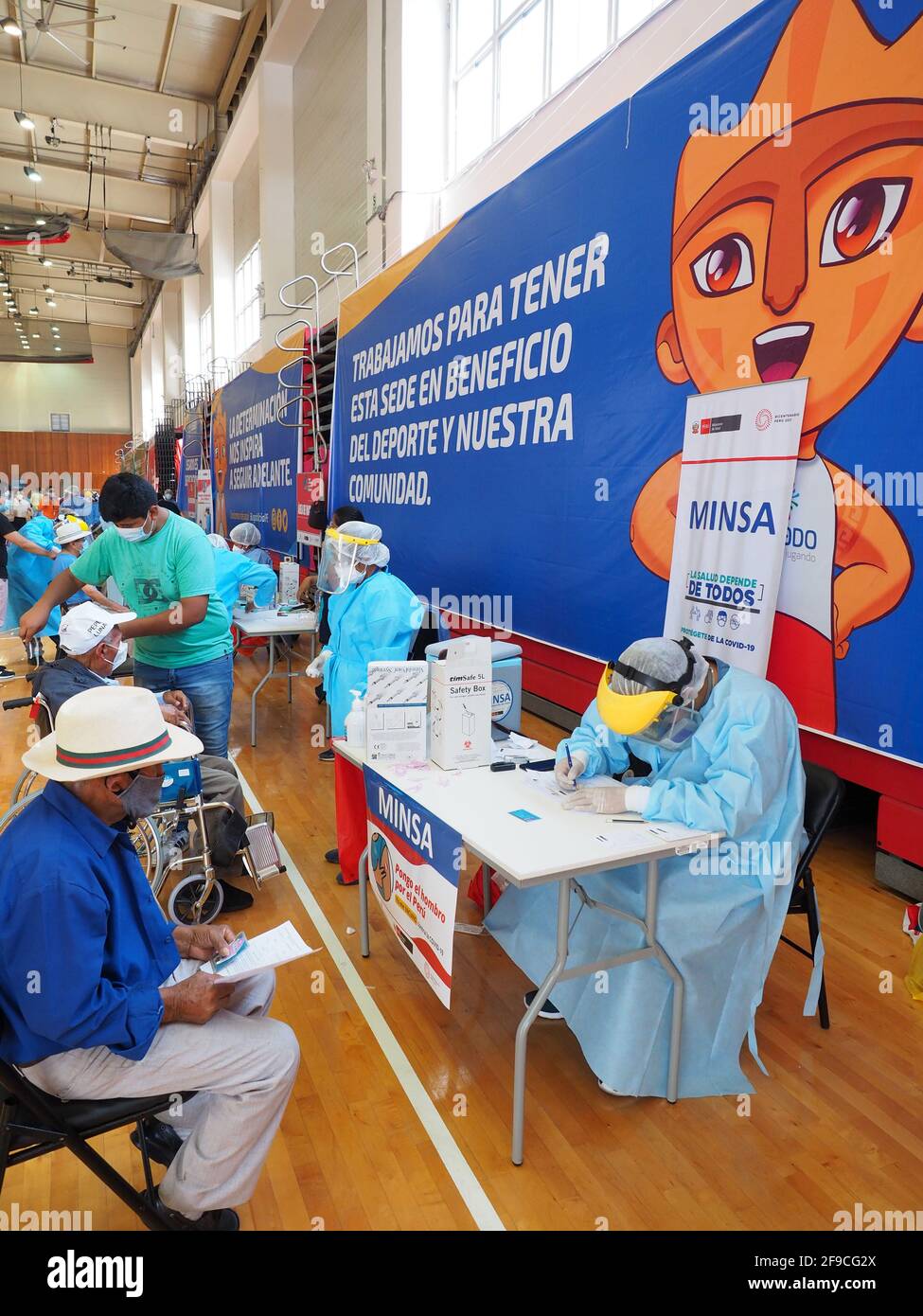 Elderly being inoculated with the Covid-19 vaccine in a sports center. The Peruvian Government enabled the sports venues of the Lima 2019 Pan American Games as vaccination centers. Stock Photo