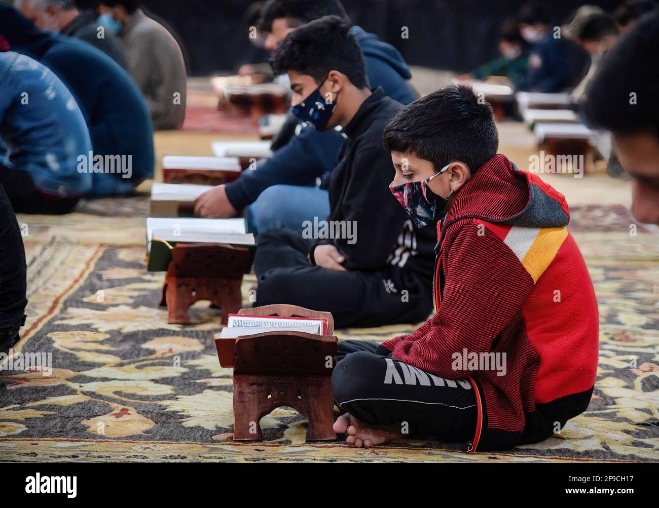 A Kashmiri Muslim boy wearing a face mask recites the Islamic Holy book ...