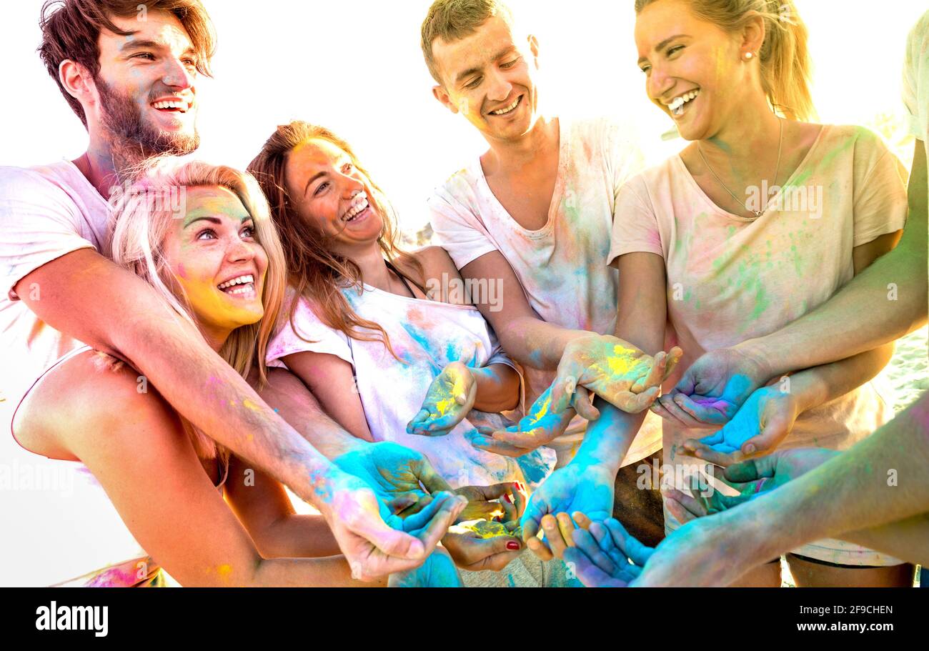 Young friends having fun at beach party on holi colors festival - Happy people playing together with genuine carefree mood at summer event Stock Photo