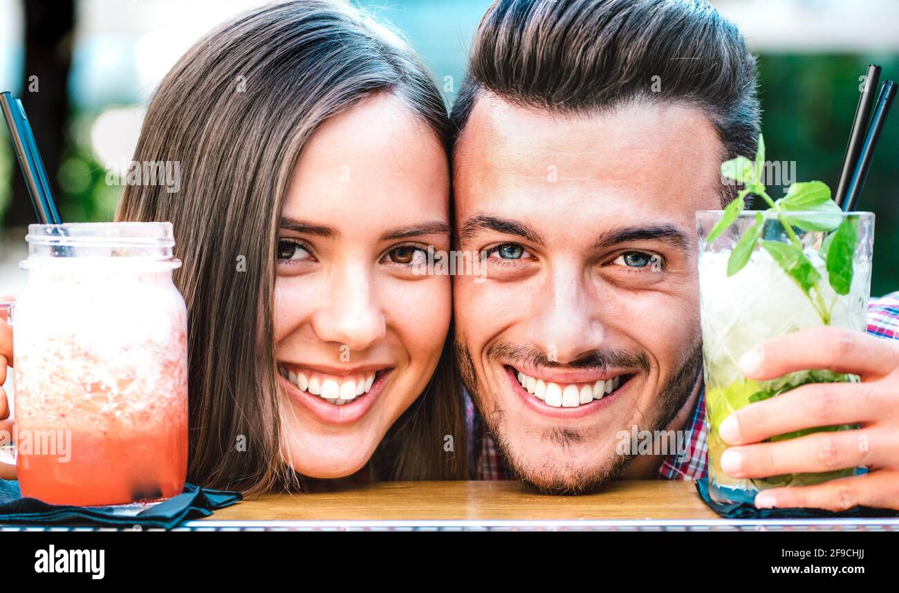 Handsome man and young woman smiling on happy hour at cocktail bar - Young lovers couple at beginning of love story - Boyfriend and girlfriend Stock Photo