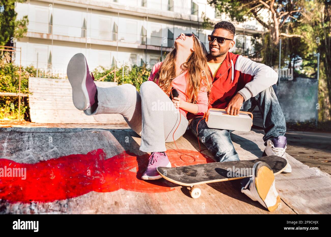Multiracial couple having fun together at skate park with music boombox - Urban life style concept with genuine people outdoors Stock Photo