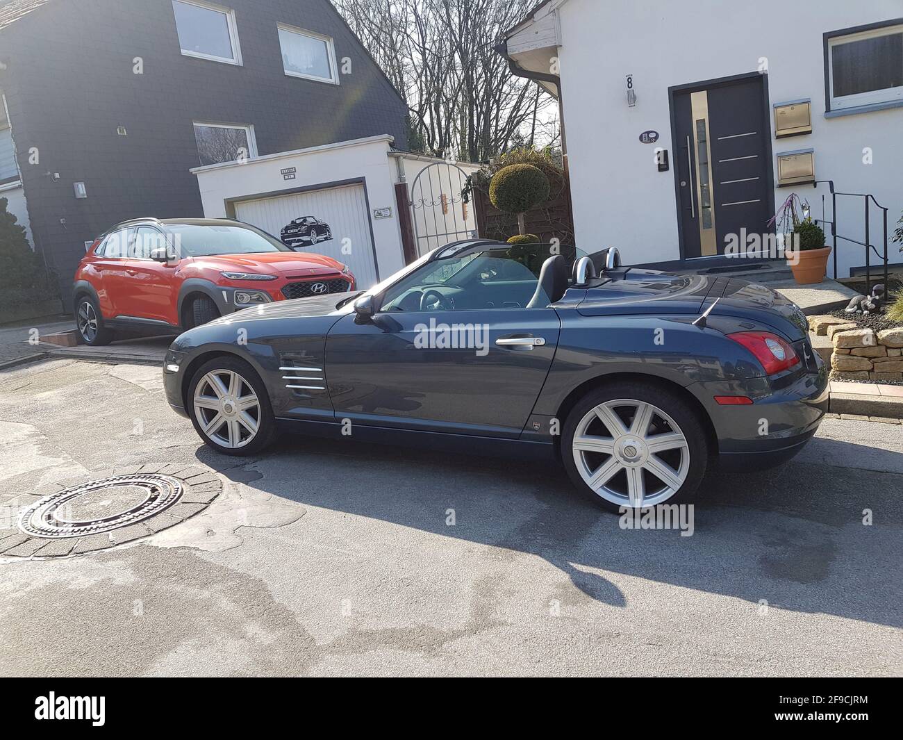 HEILIGENHAUS, NRW, GERMANY - MARCH 28, 2020: A Hyundai Kona SUV and Chrysler Crossfire Roadster park in front of a house Stock Photo