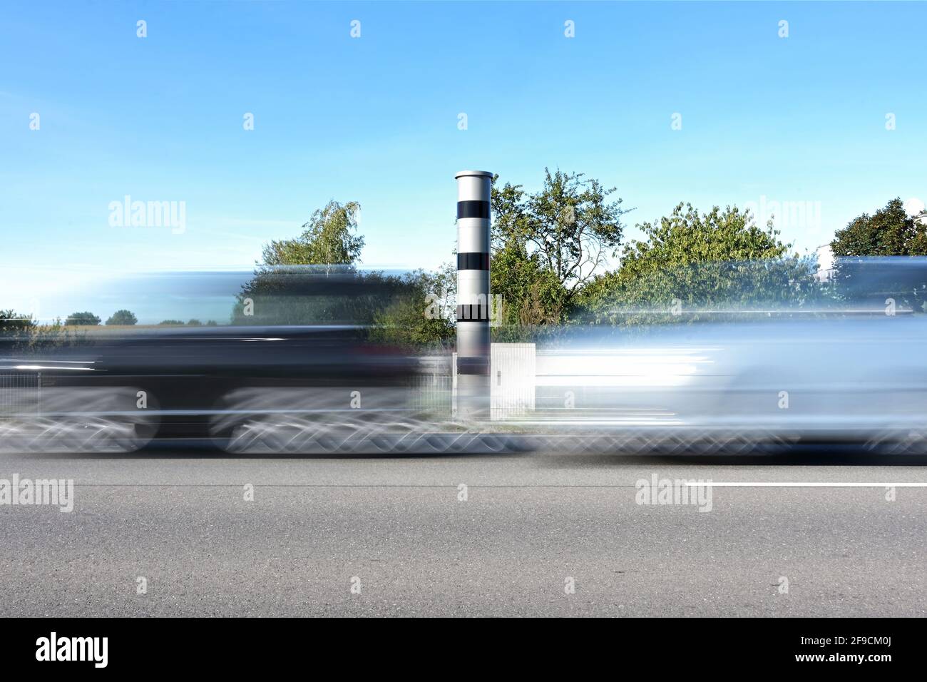 Fast cars in motion blur in front of an automatic speed measurement with light radar and camera for traffic enforcement, speeding may result in a mone Stock Photo