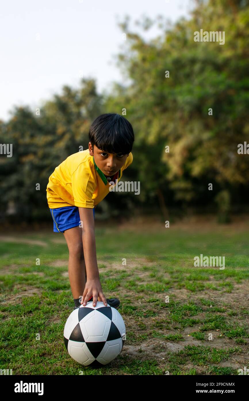 Young boy Sitting in the ground with football Stock Photo