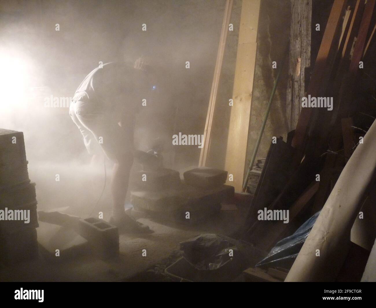 Construction worker cuts cement in a dusty workshop Stock Photo