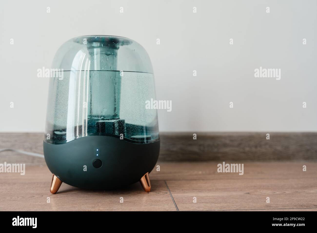 Modern air humidifier on a white wall background. Humidifier spreading steam into the living room Stock Photo