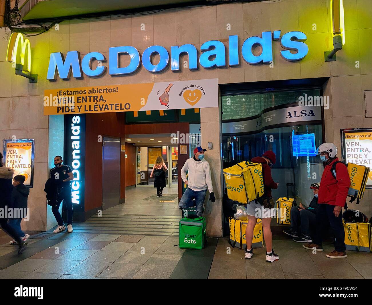 Oviedo, Spain - December 13, 2020: Couriers for the delivery services Glovo and Uber at the entrance of a McDonalds restaurant in Oviedo, Spain Stock Photo