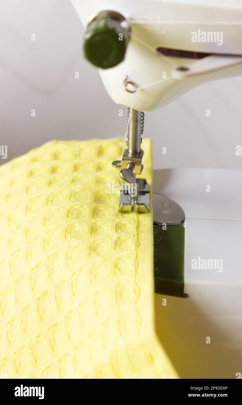 Part of a sewing machine and a bright yellow fabric. Tailor's work