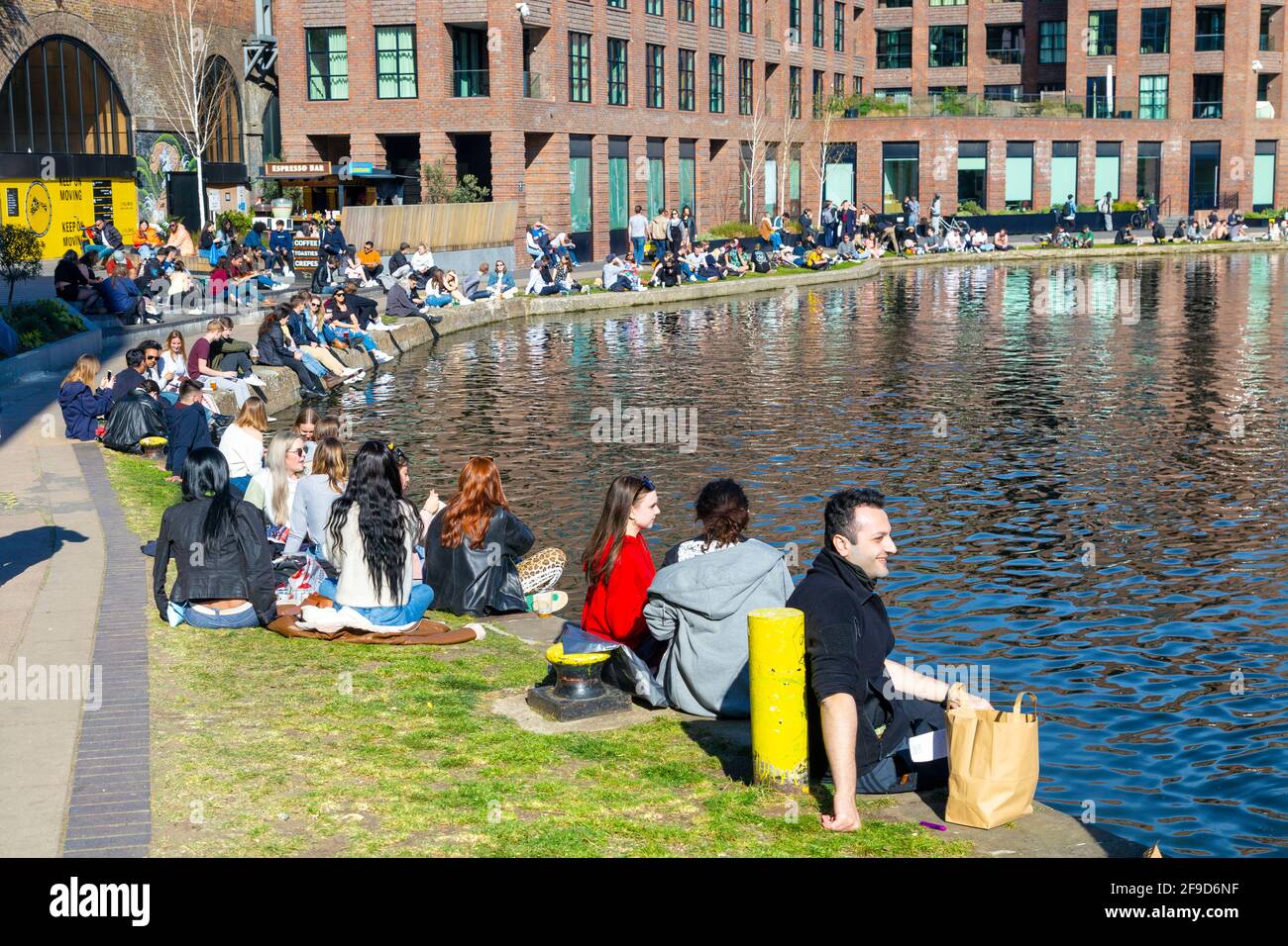 17th April 2021 - London, UK, People sitting along Regents Canal in Camden on a sunny weekend after easing of coronavirus pandemic lockdown Stock Photo