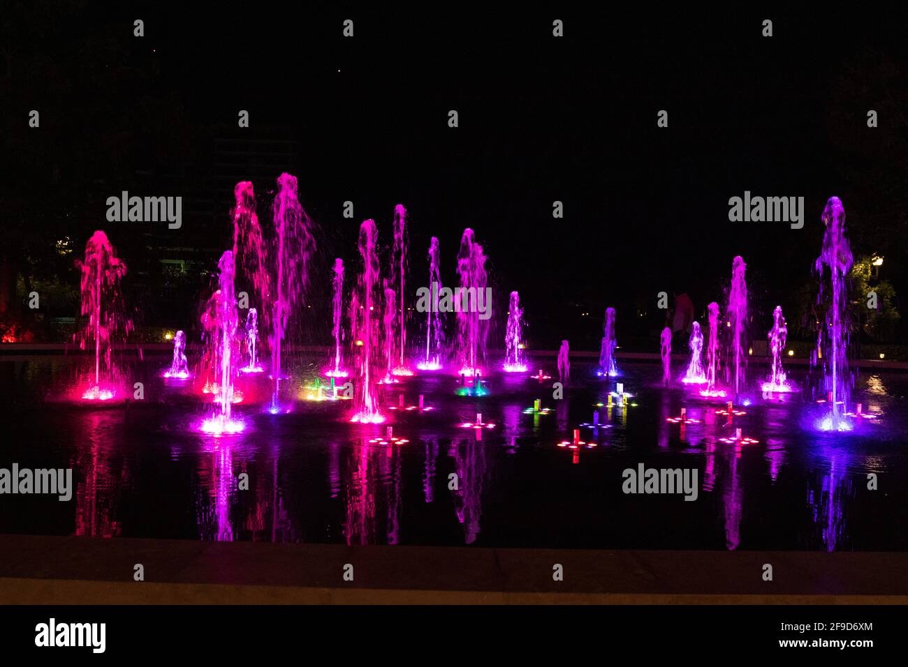 Bright colourful fountain against a dark sky Stock Photo