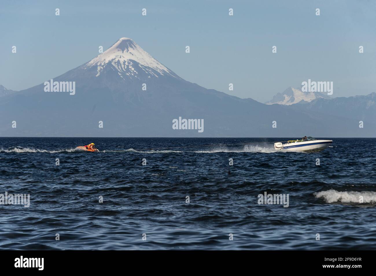 FRUTILLAR, CHILE - Feb 17, 2021: Boats passing by and bathers enjoying the summer in the water at Lake Llanquihue Stock Photo