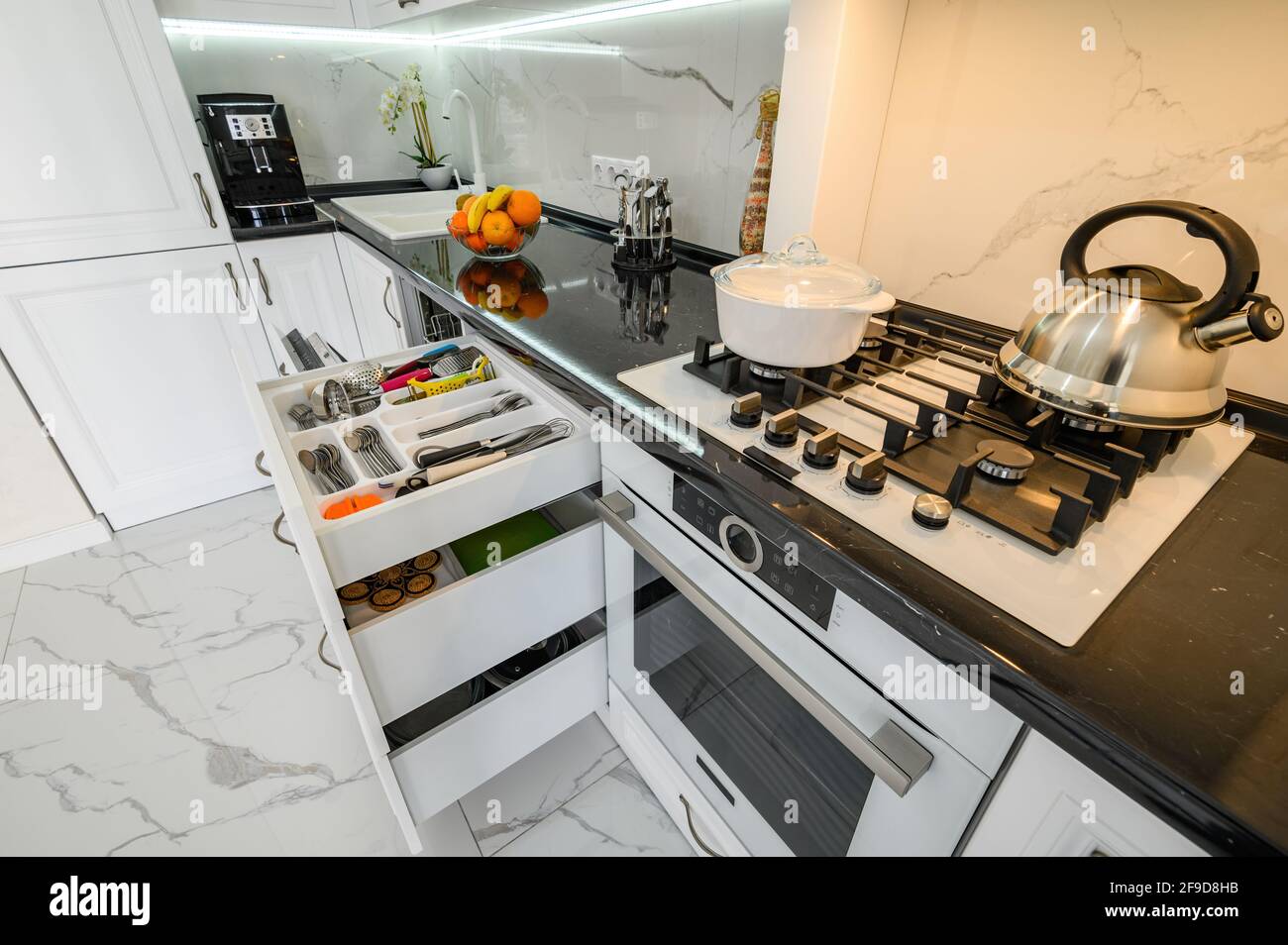 Luxurious white modern kitchen interior, drawers pulled out, dishwasher