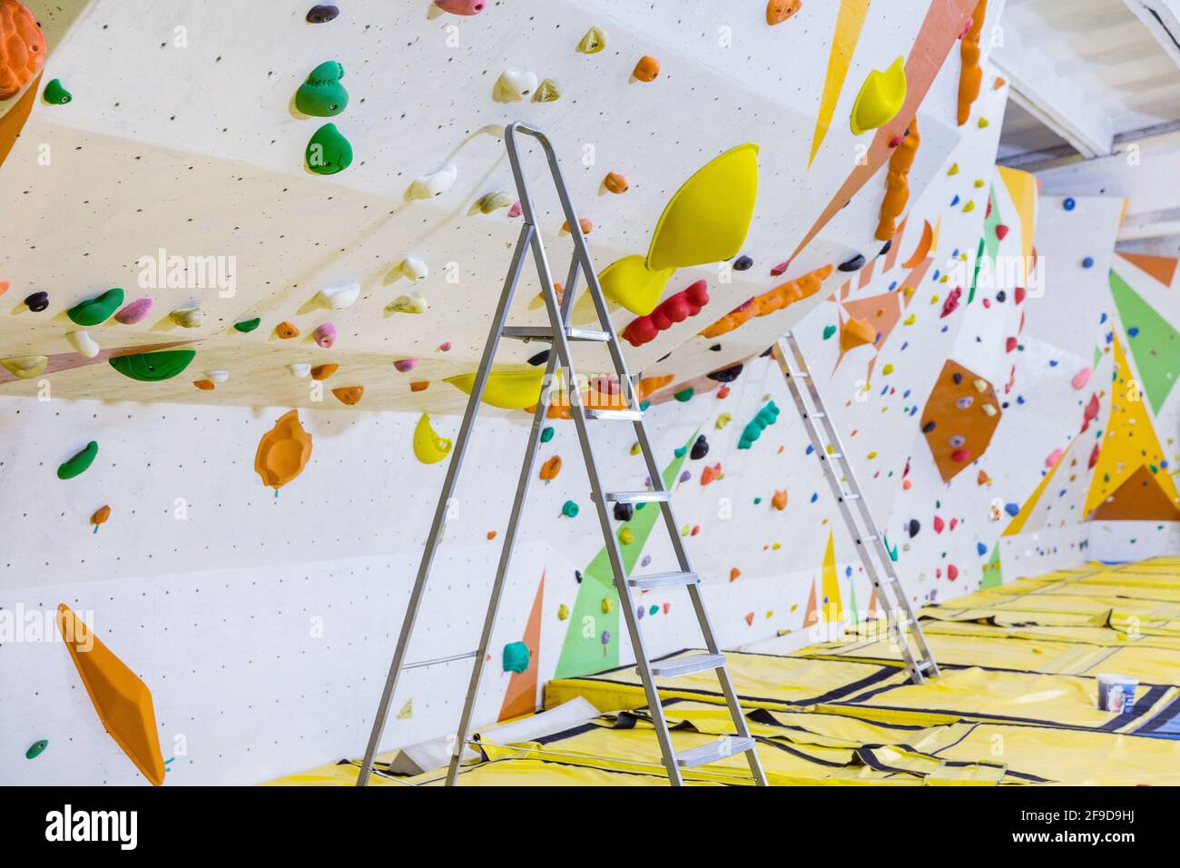 Empty indoor bouldering gym with ladders next to climbing walls ...