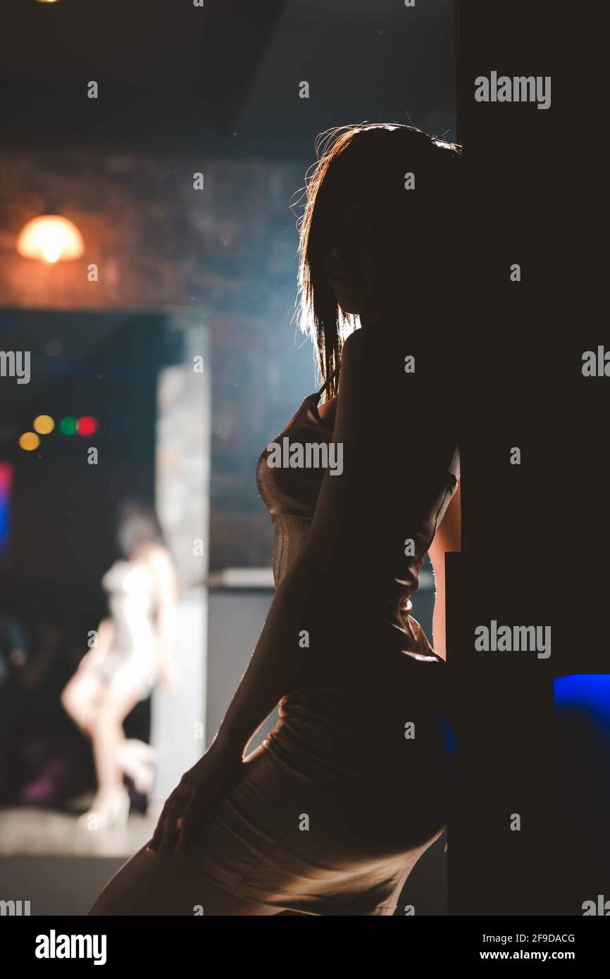 Shallow focus of a woman in a tight dress posing in a club under the lights Stock Photo