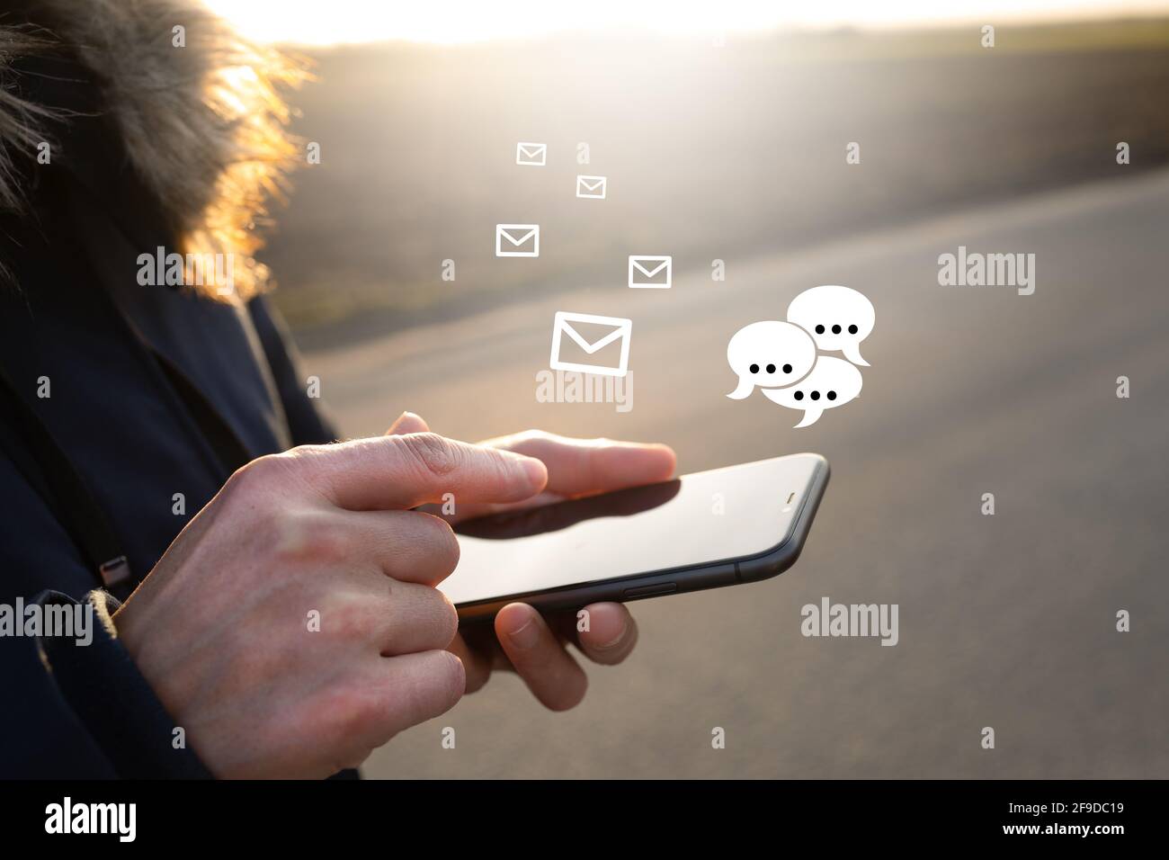 Unrecognizable man holding a smartphone and getting notifications while standing outdoors Stock Photo