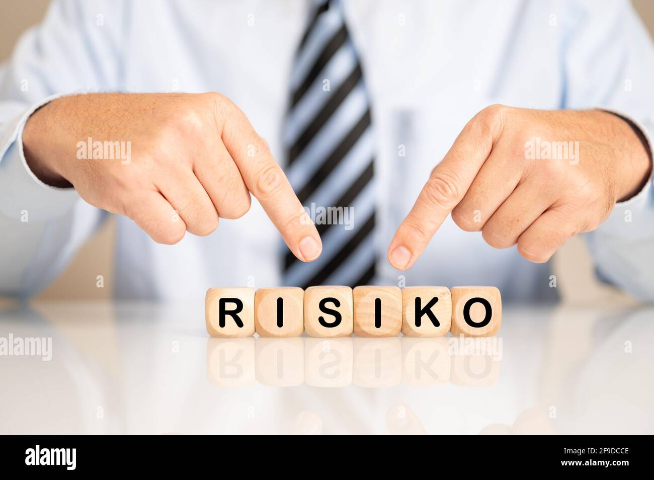 Male hand pointing to wooden cubes with the letters making the word risiko Stock Photo