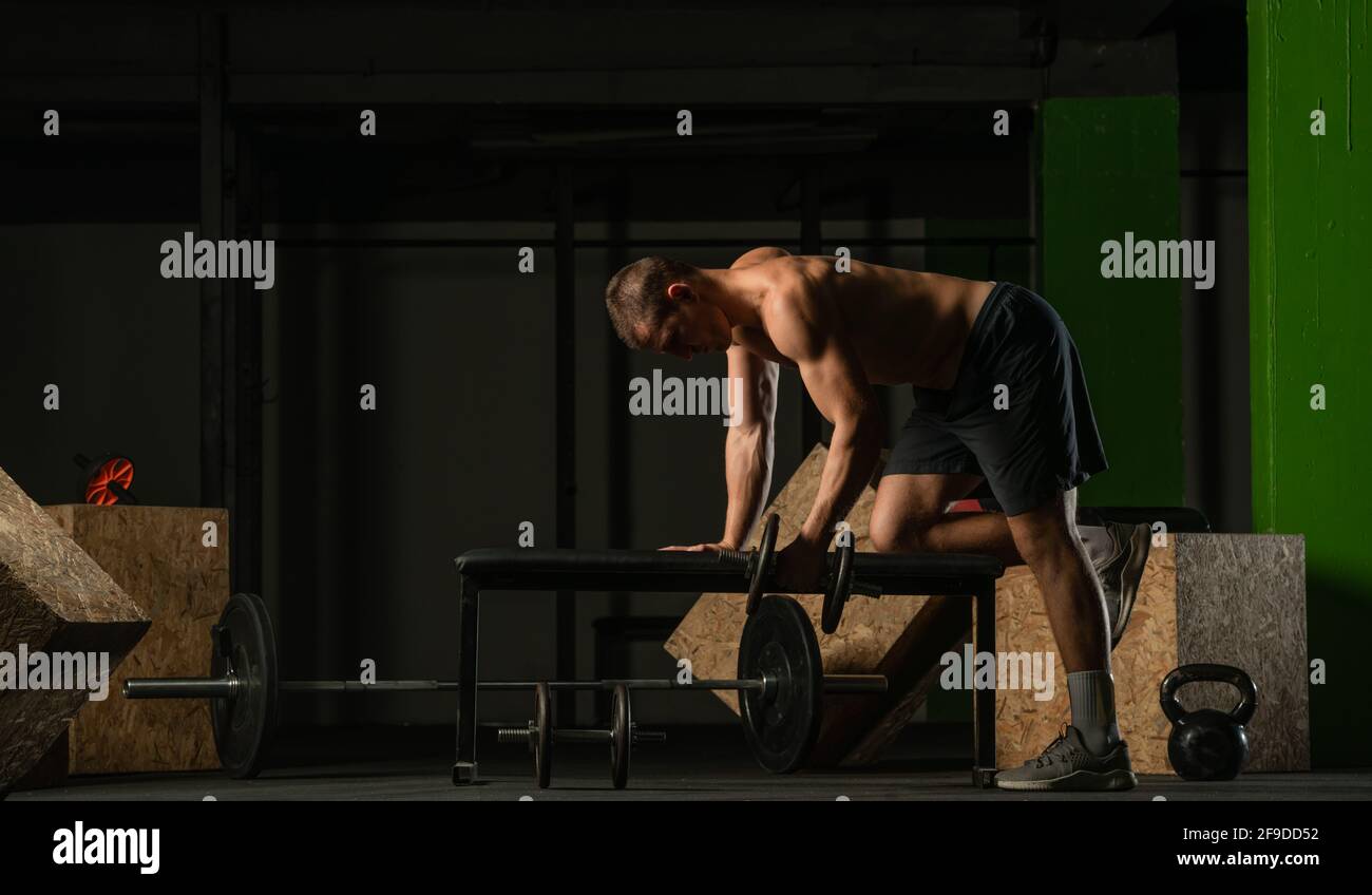 Good looking young man doing triceps dumbbell kickback exercises with