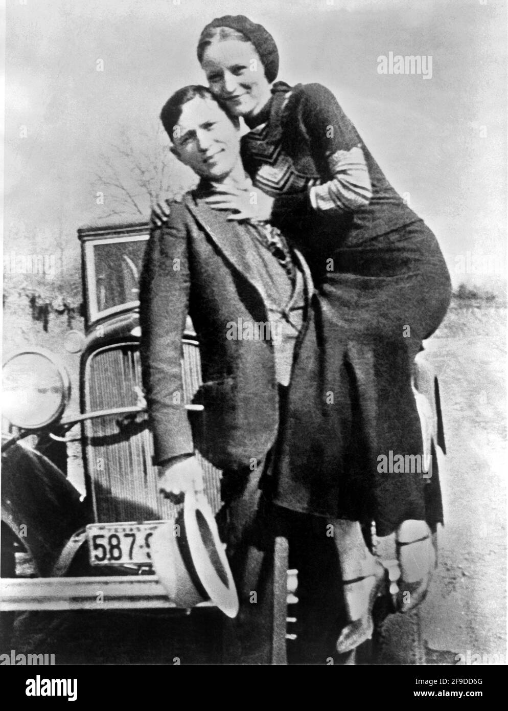 1934 , Arkansas , USA : The famous gangsterns  BONNIE PARKER  ( 1910 - 1934 ) and CLYDE BARROW ( 1909 - 1934 ). Contrary to popular belief the two never married. They were in a long standing relationship. Posing in front of a 1932 Ford V8 automobile where Bonnie and Clyde dead on May 23, 1934 . Unknown photographer . - OUTLAWS - KILLER - ASSASSINO - delinquente - criminalità organizzata  - GANGSTERN - Bos - CRONACA NERA - CRIMINALE - car - automobile - hat - cappello - embrace - abbraccio ---  Archivio GBB Stock Photo