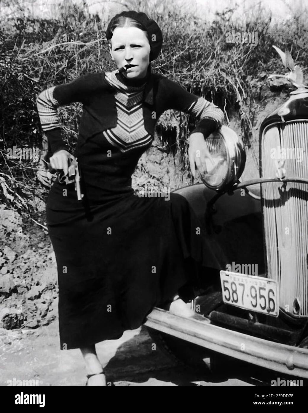 1934 , Arkansas , USA : BONNIE with revolver smoke a cigar . Of The famous  gangsterns couple BONNIE PARKER ( 1910 - 1934 ) and CLYDE BARROW ( 1909 -  1934 ).