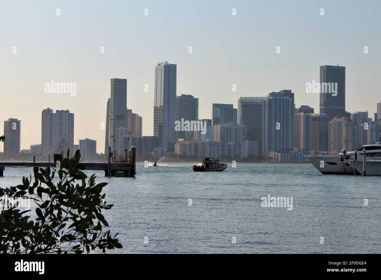 Tug boat going to save a yacht from the ocean in the Biscayne bay harbor inlet during sunset. Downtown Miami cityscape in the background. Stock Photo