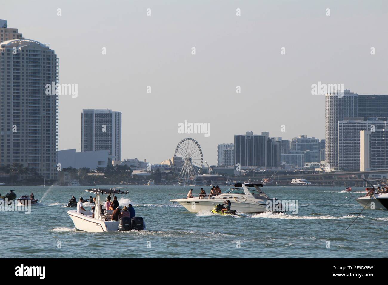 Boats traveling along Biscayne bay Brickell and Downtown Miami cityscape in the background. Boats are parking in the bay inlet to watch the sunset Stock Photo