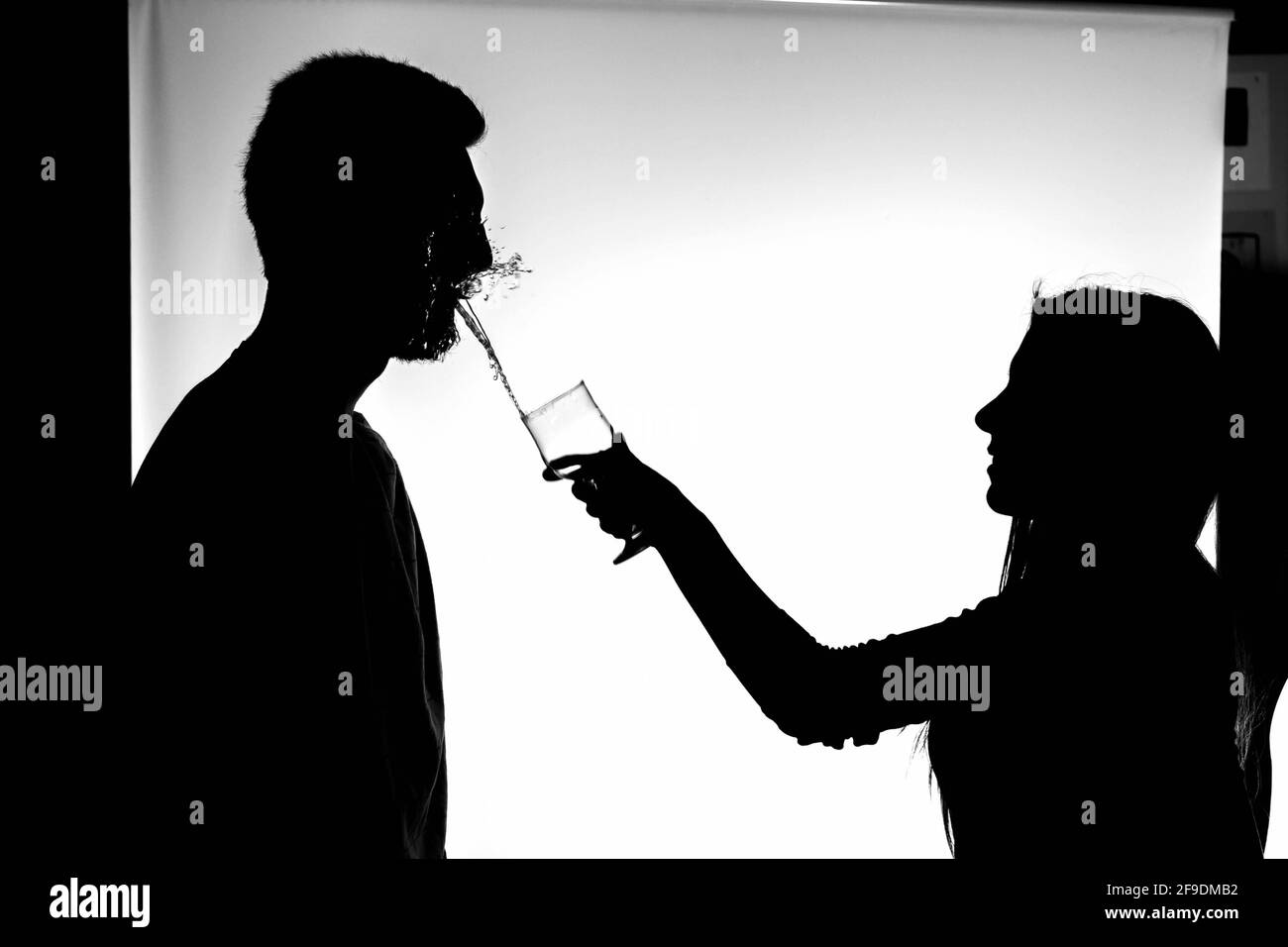 A black silhouette of a girl throwing a glass of water on her