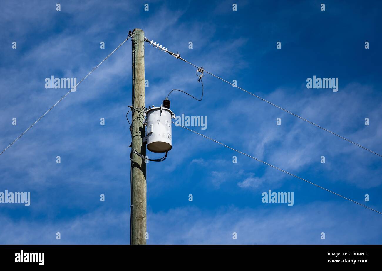 A wooden power pole with with a transformer and power lines on a rural property in North America. Stock Photo