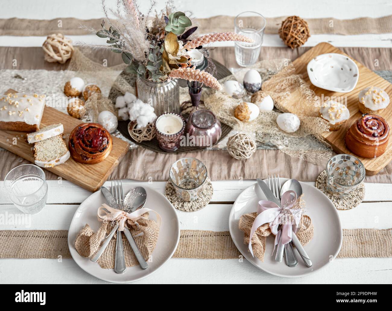 A festive table with beautiful dishes, decorative items and pastries. Easter table setting design idea. Stock Photo