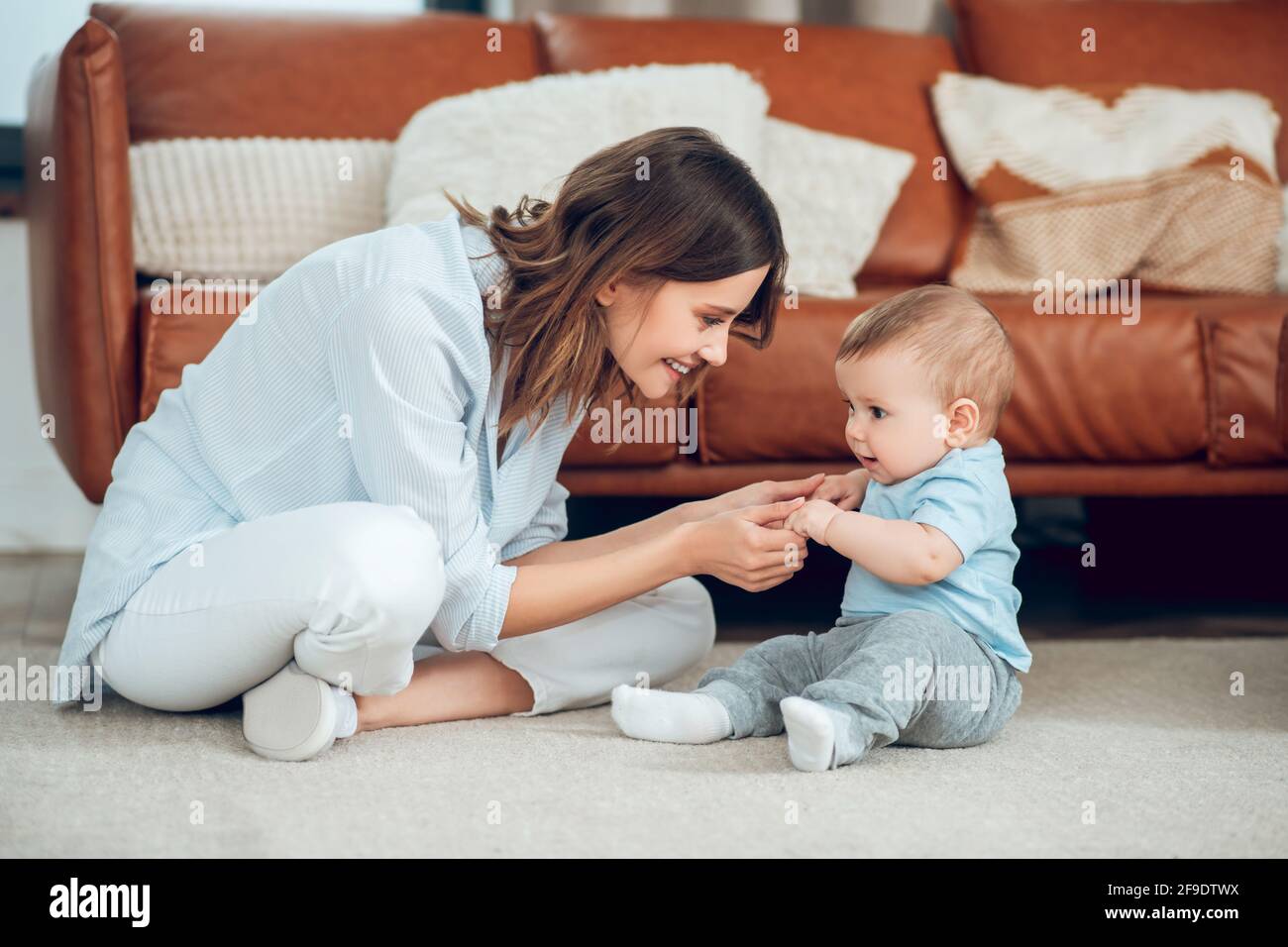 Mom and baby sitting on floor opposite each other Stock Photo