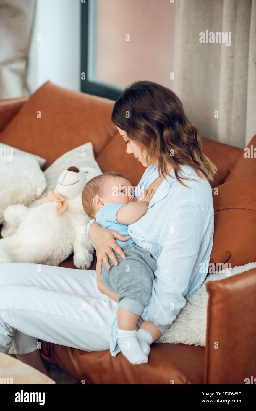 Mom feeding her baby sitting on couch Stock Photo
