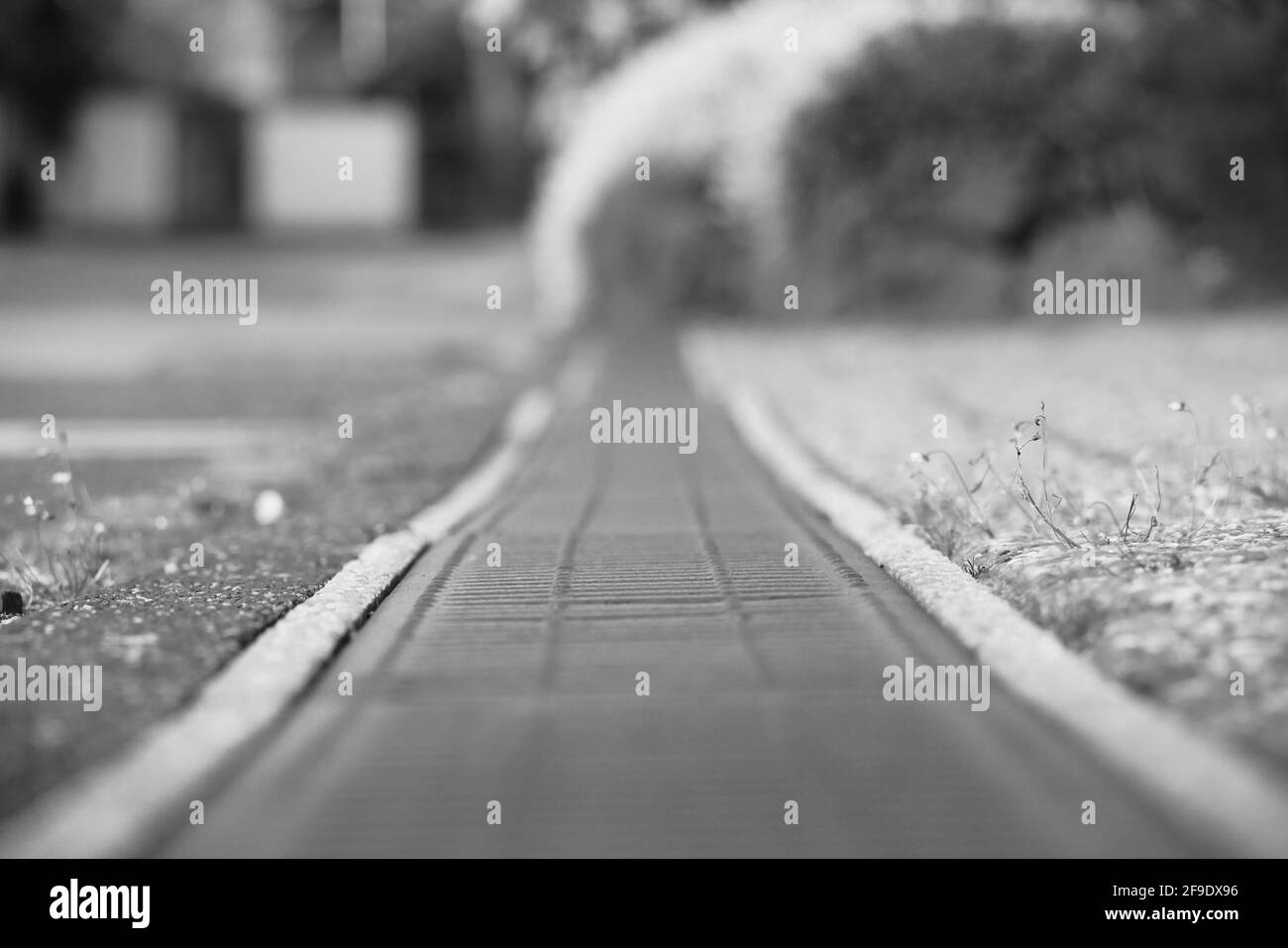 close up of a rain drainage grate on the street in the city in black and white Stock Photo