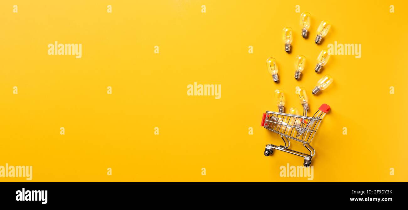 creativity content marketing concept,top view shopping cart with full of lightbulbs with on yellow desk surface.leave space for display your content. Stock Photo