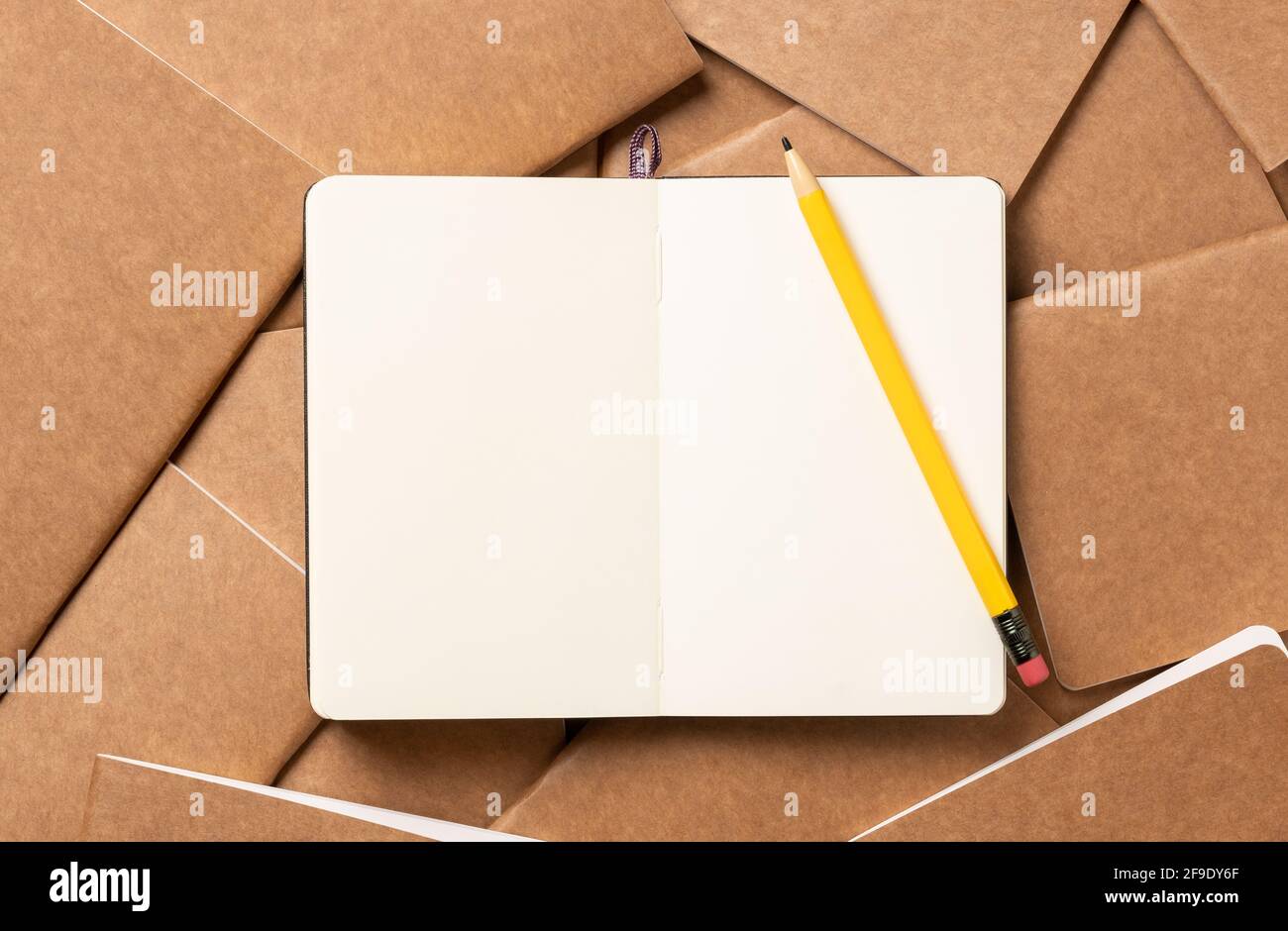 open notebook with pencil on brown kraft notebook disorder alignment on table background.mockup template for display content or design.content marketi Stock Photo