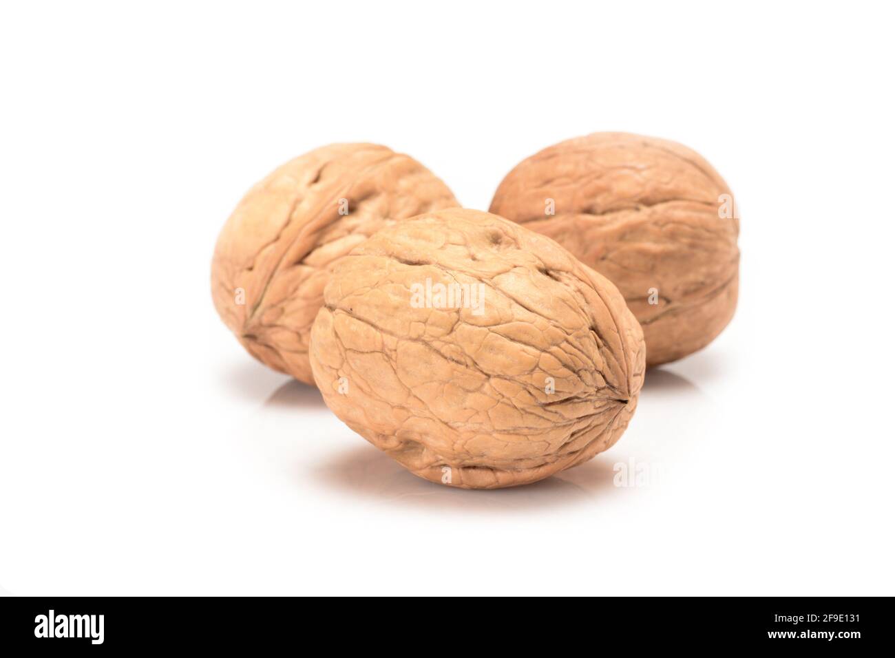 Three whole walnuts, close-up macro, isolated on a white background. Stock Photo
