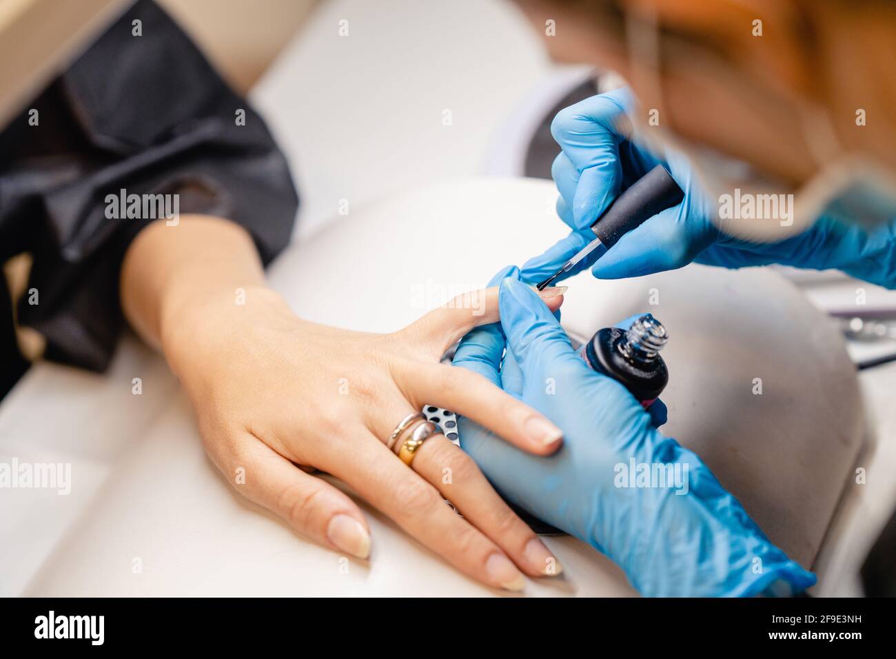 Manicurist paints nails with gel polish on clients nails. Stock Photo