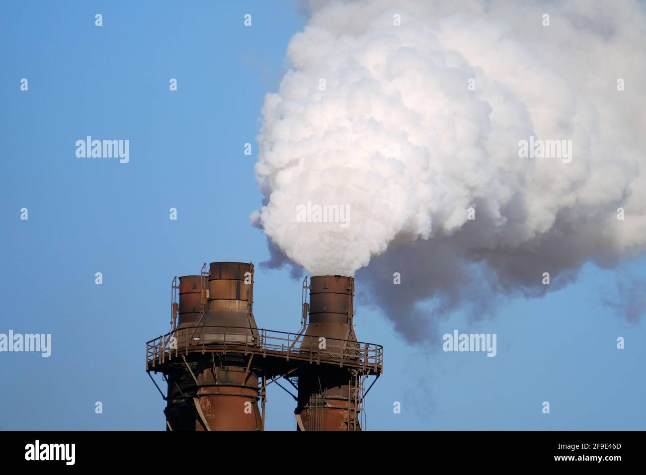 Smoke and steam emitting from steelmaking plant stacks. Stock Photo