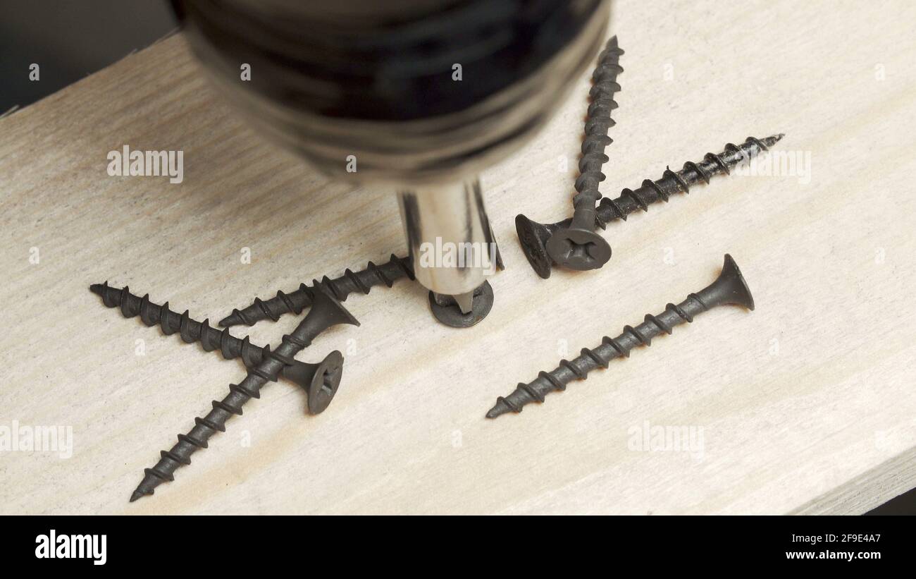 Photo of screwdriver drilling an tapping screws into a board Stock