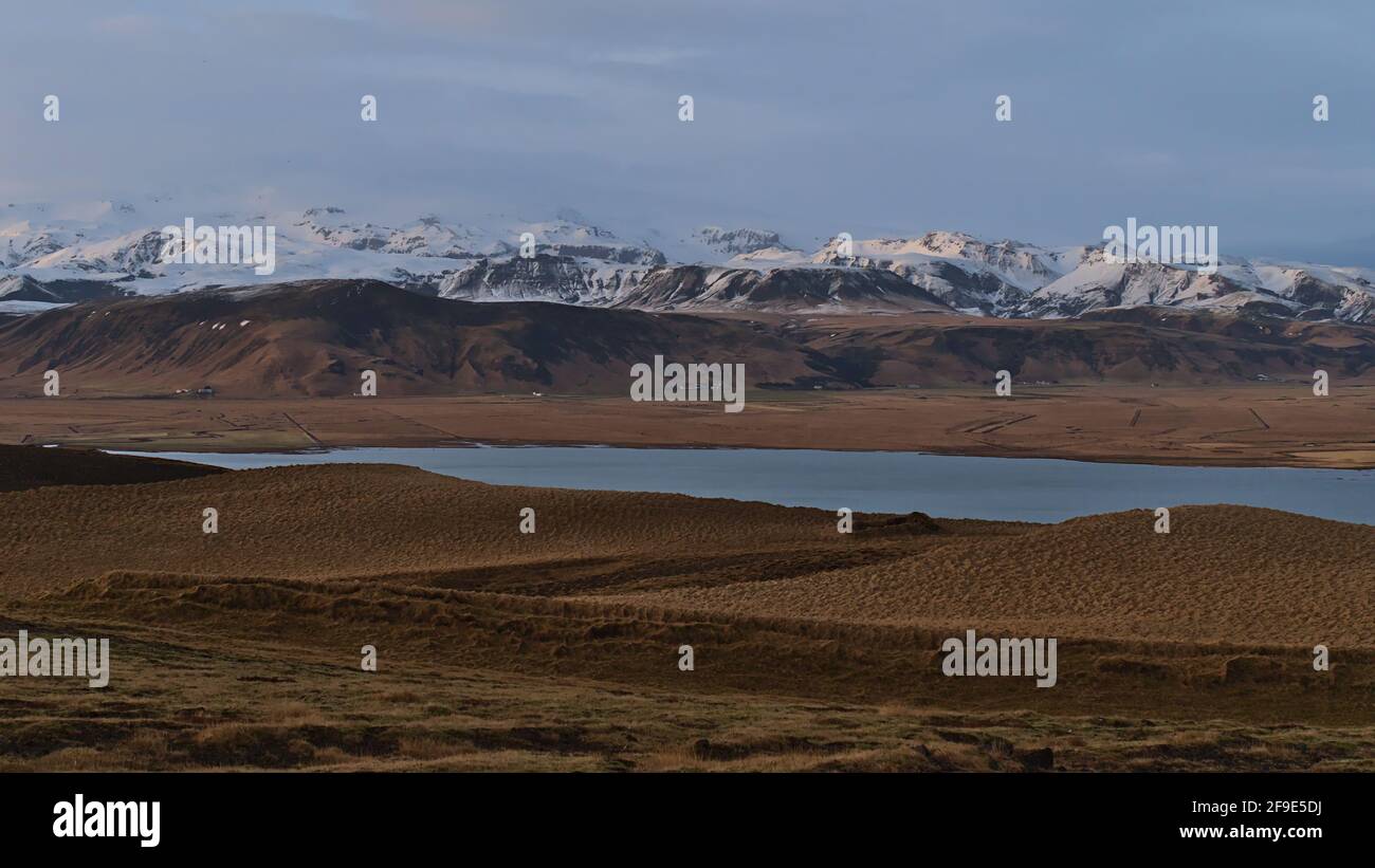 Beautiful panoramic view of snow-capped foothills of ice cap Mýrdalsjökull, covering volcano Katla, in evening light viewed from Dyrhólaey, Iceland. Stock Photo