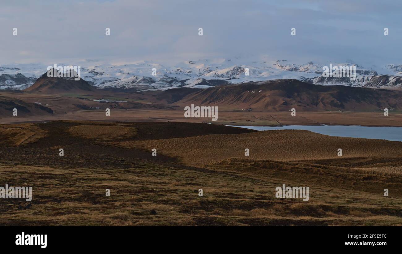 Stunning panoramic view of the snow-covered rugged foothills of Mýrdalsjökull glacier, covering volcano Katla, in evening sunlight in Iceland. Stock Photo
