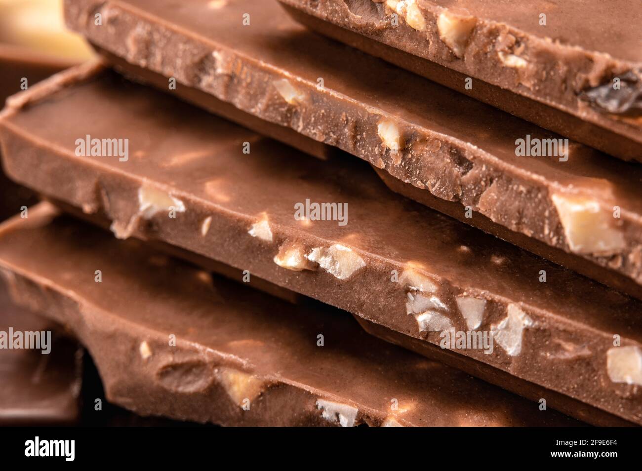 Close up of Belgian milk chocolate. Stack of milk and dark chocolate with  nuts. Heap of chocolate bars. side view. Bitter chocolate on  blurredbackgrou Stock Photo - Alamy