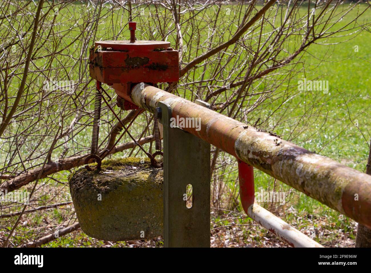Old red and white manual operated lift barrier on a forest road with a