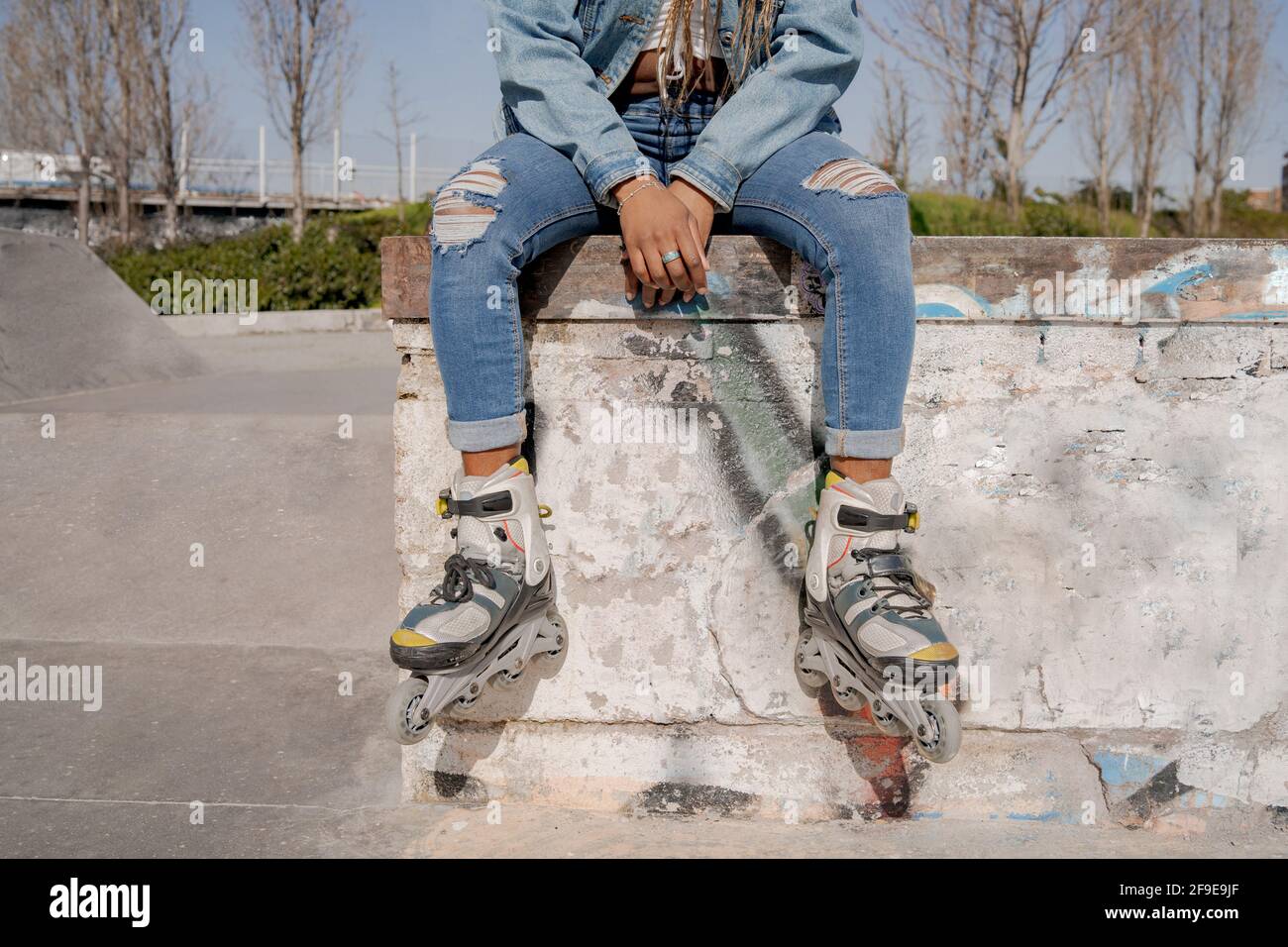 Crop black female with braided hairstyle and in rollerblades sitting on ...