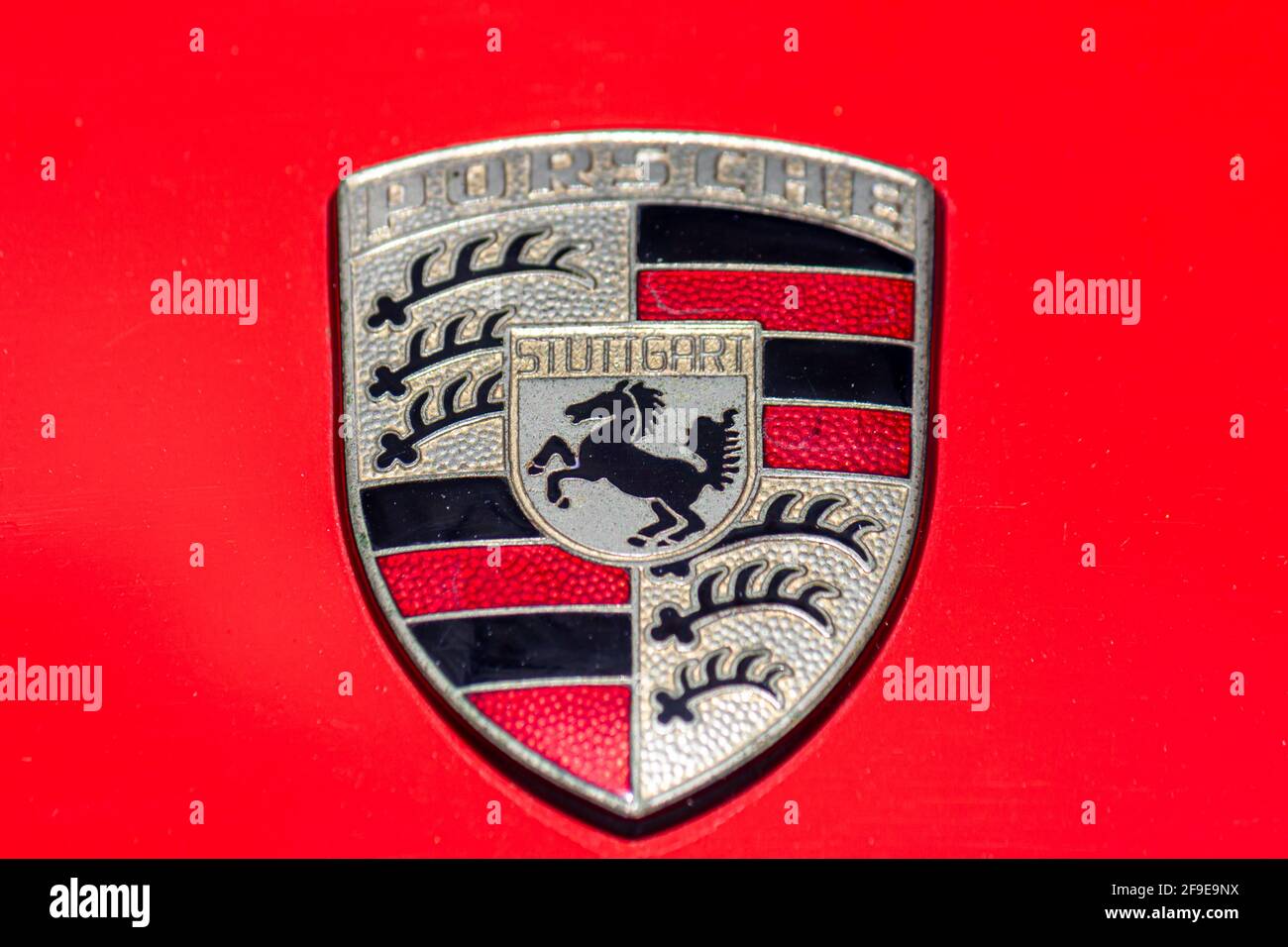 Original Porsche crest isolated on red background (car hood) Stock Photo
