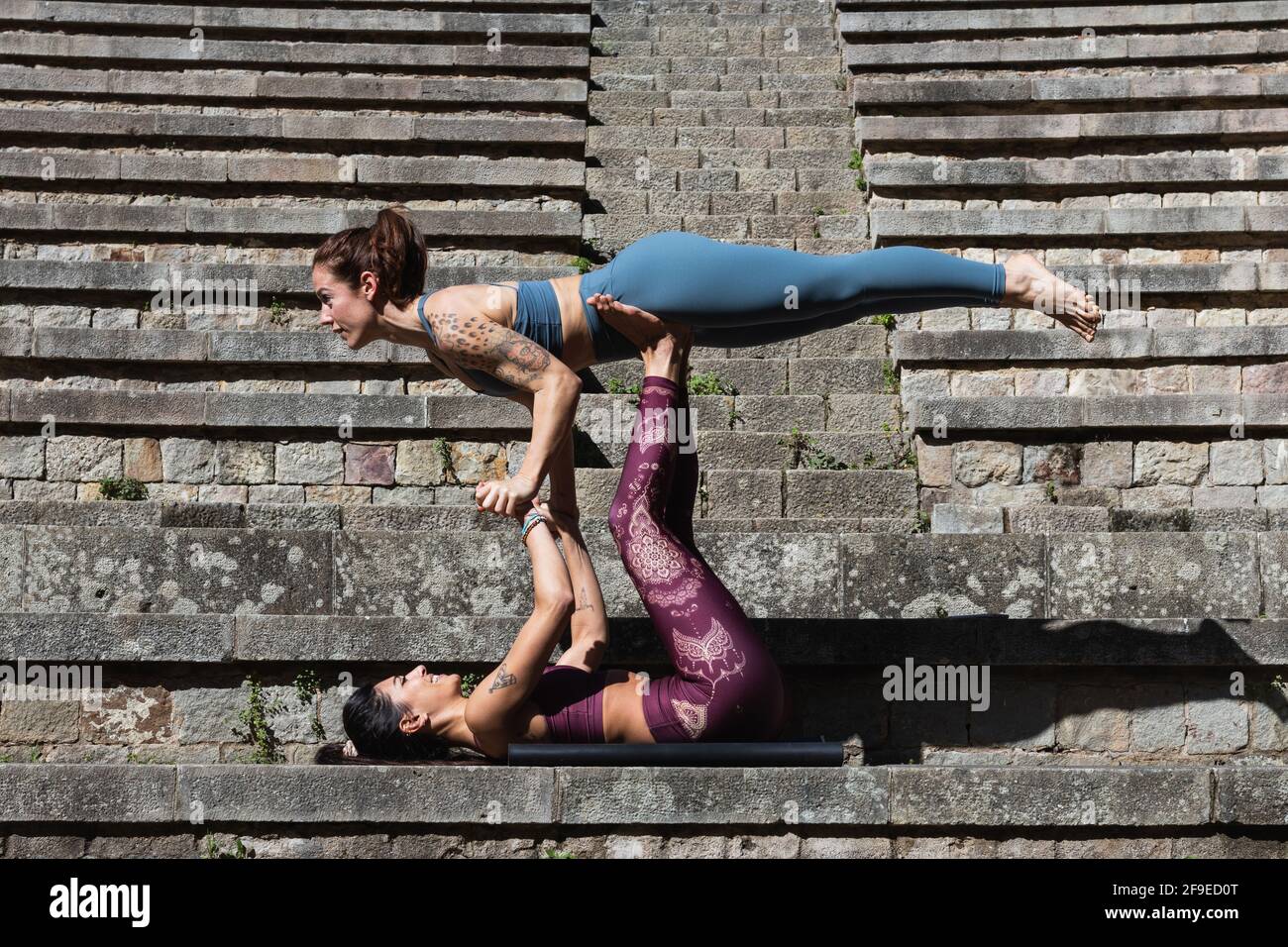 Side view of flexible female supporting Woman on legs while practicing ...