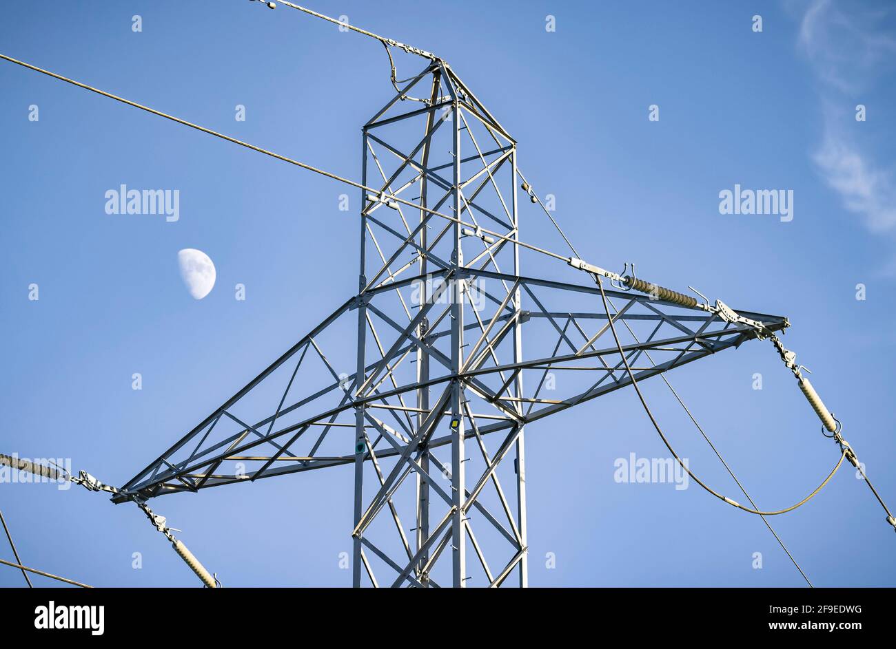Detail of electricity pylon with the moon against a blue sky, depicting UK National Grid and electricity power supply Stock Photo