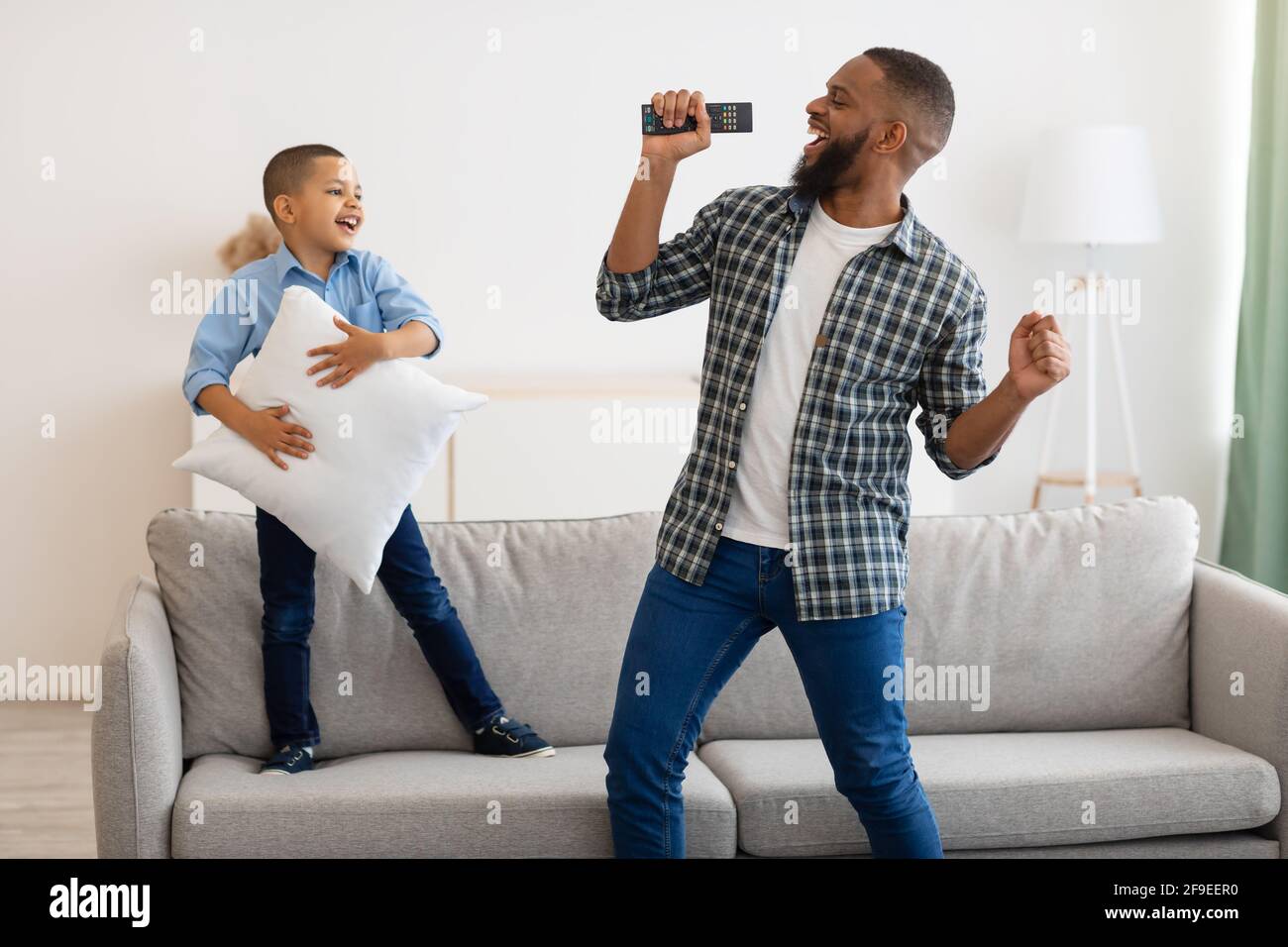 Joyful Black Dad And Son Singing And Dancing At Home Stock Photo