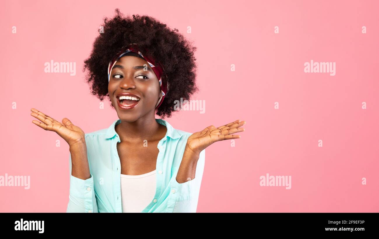 Cheerful Black Lady Shrugging Shoulders Looking Aside Over Pink Background Stock Photo