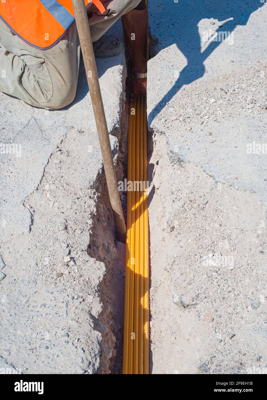 Worker inserts fiber optic cables buried in a micro trench Stock Photo ...