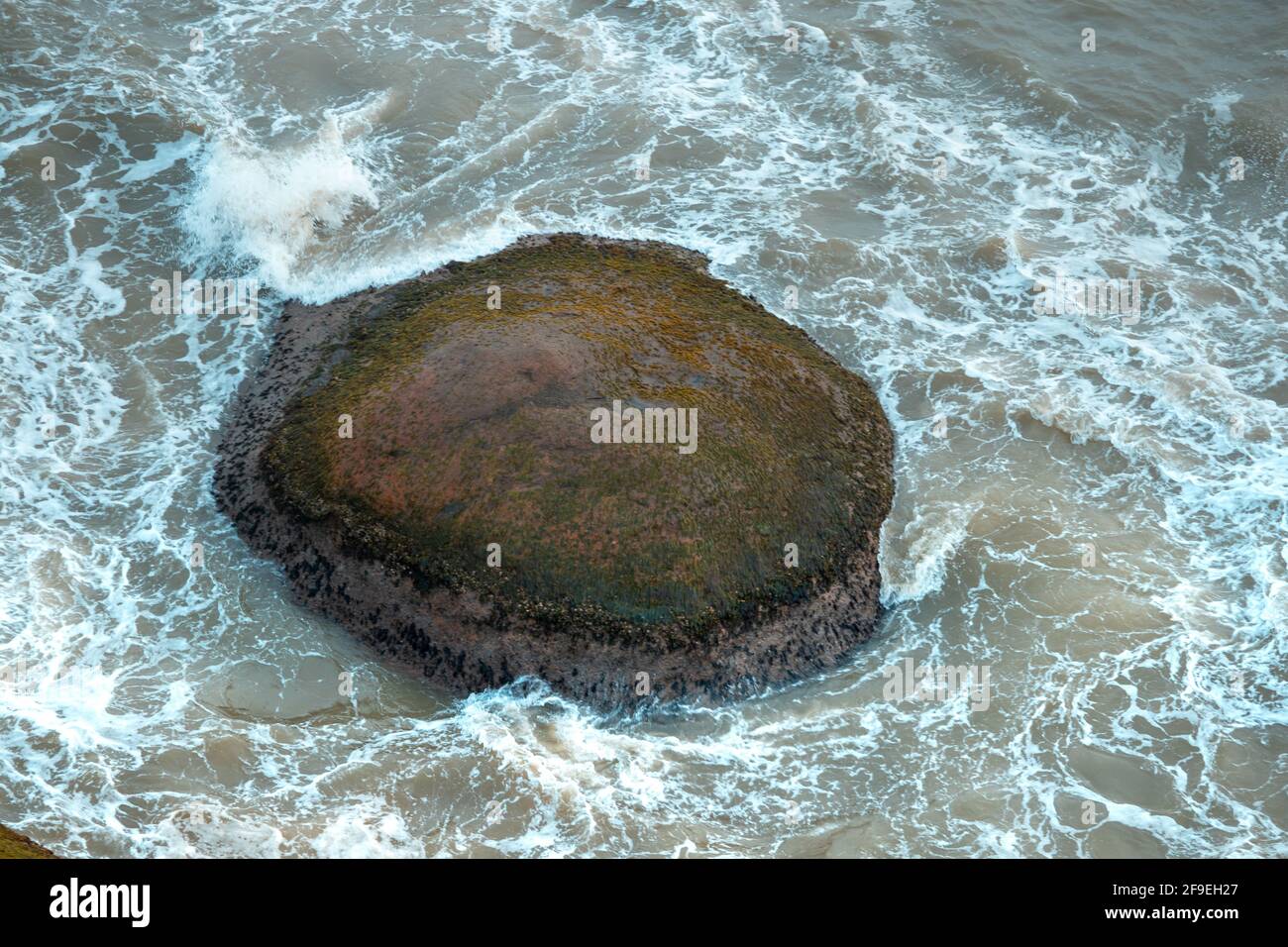 An aerial top view of sea waves hitting rocks on the beach Stock Photo ...